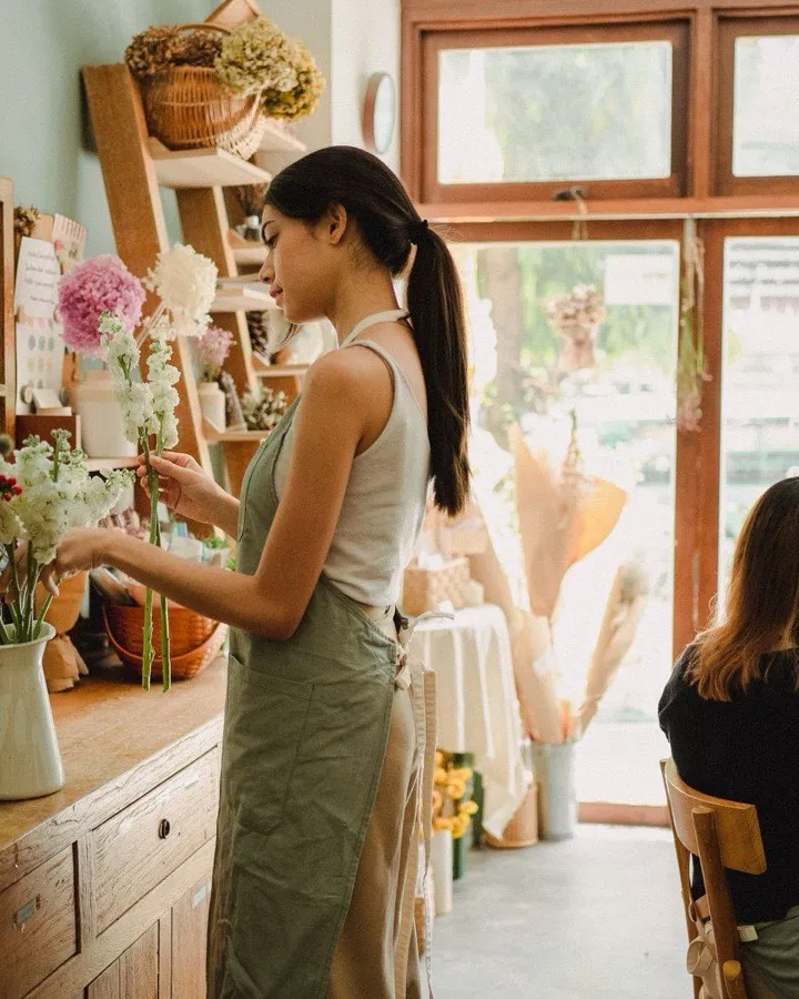 Une fleuriste composant un bouquet dans sa boutique